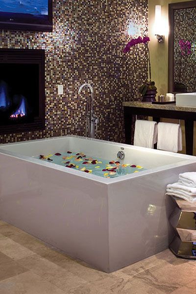 A photo of an oversized Villa bathtub filled with scented water and petals and ready for a relaxing SPA session. 