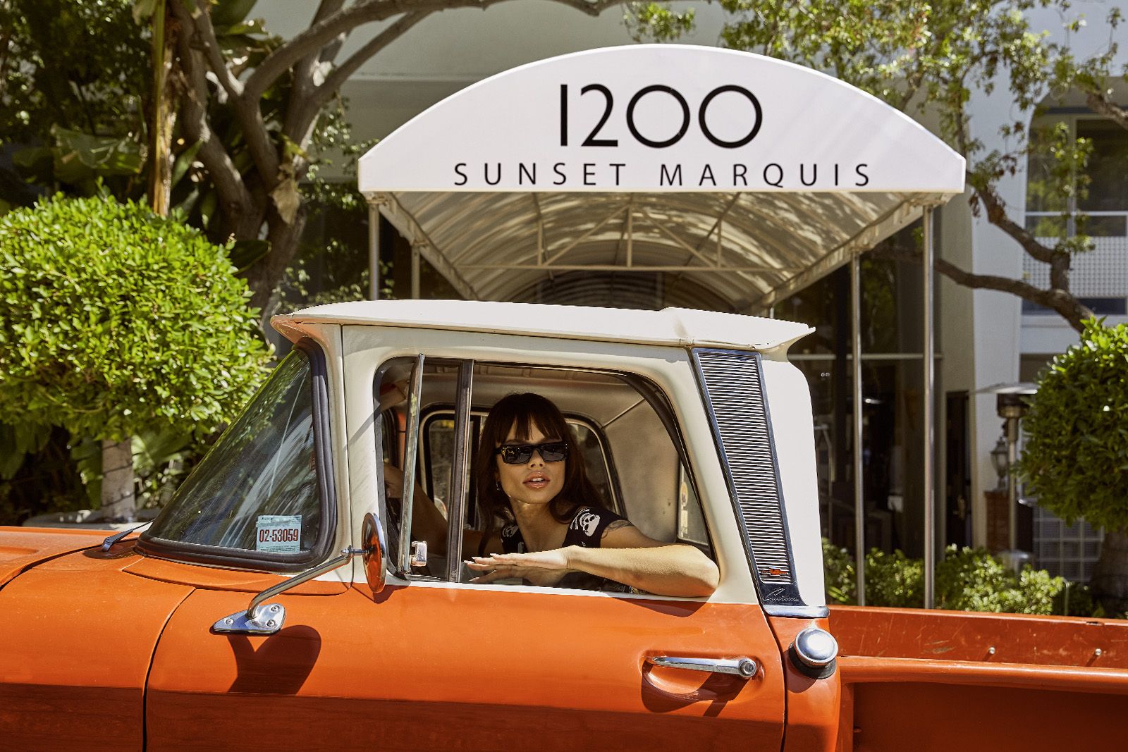 Woman in vintage truck under the Sunset Marquis awning
