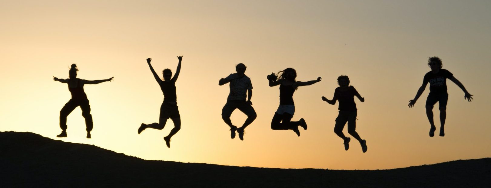 Silhouettes of a Group of People Jumping at Sunset